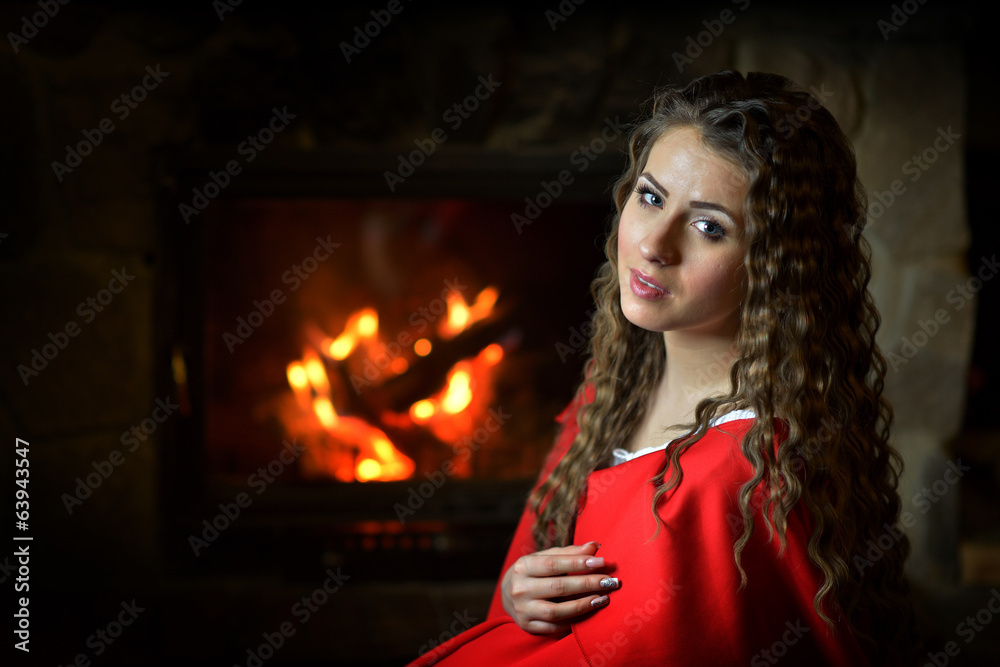 beautiful woman with red cloak sitting by the fire