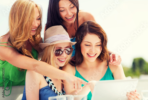 girls looking at tablet pc in cafe