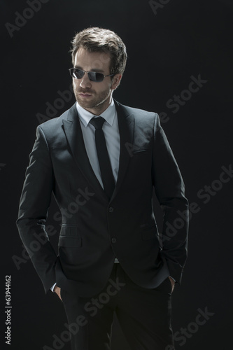 handsome man in black suit on a black background © jackfrog