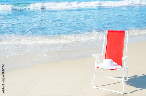 Beach chair with white hat by the ocean