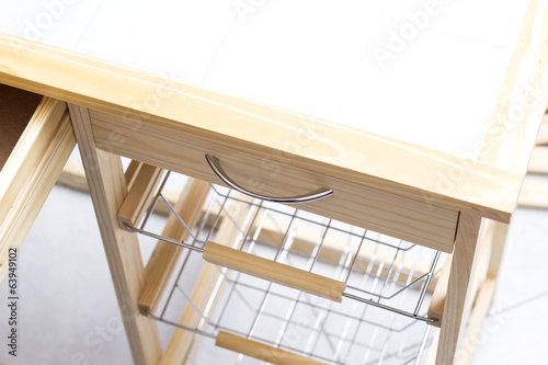 A carpenter builds a small white table with a screwdriver