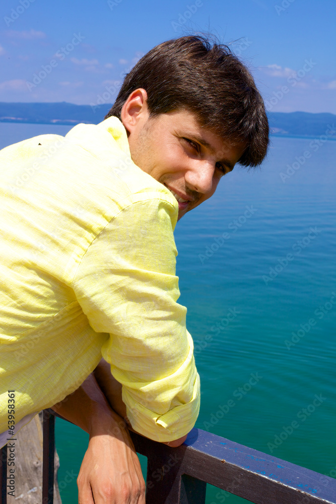 Handsome italian man smiling in vacation in front of lake