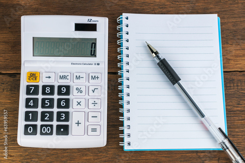 Calculator with notebook & pen on wooden background