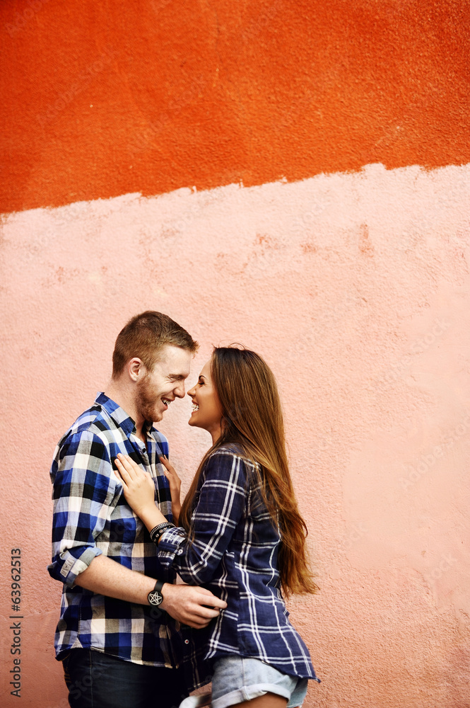 Loving couple embracing on a red wall