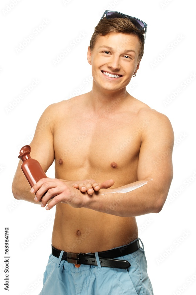 Cheerful young man applying sunscreen cream