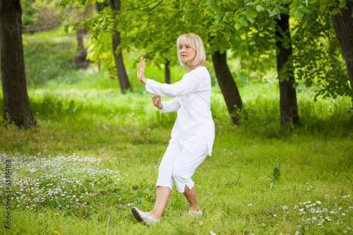 senior woman in white practising tai chi