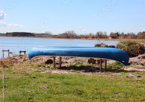 Canoe placed at beach with blue sky and water front