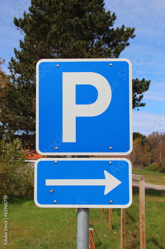 Blue parkinglot sign with right arrow and sky in background