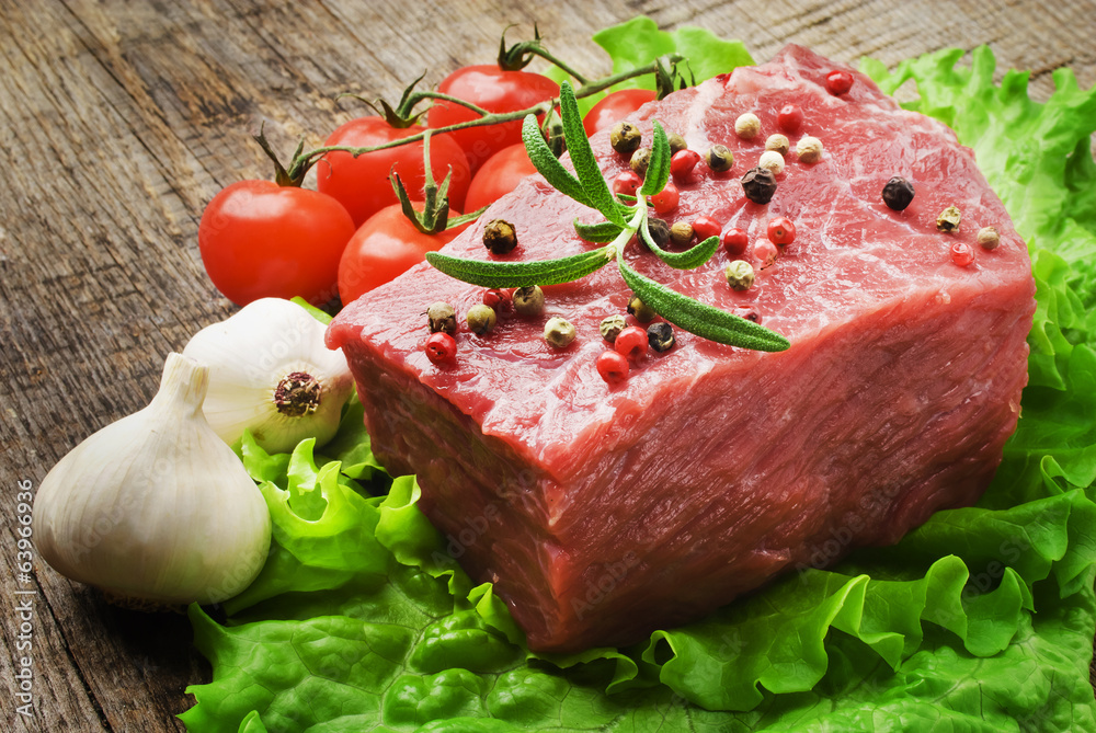 Raw Steak with green lettuce on wooden board Raw Steak with green lettuce on wooden board