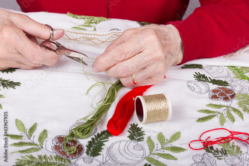 Seniorin beim Sticken einer Tischdecke