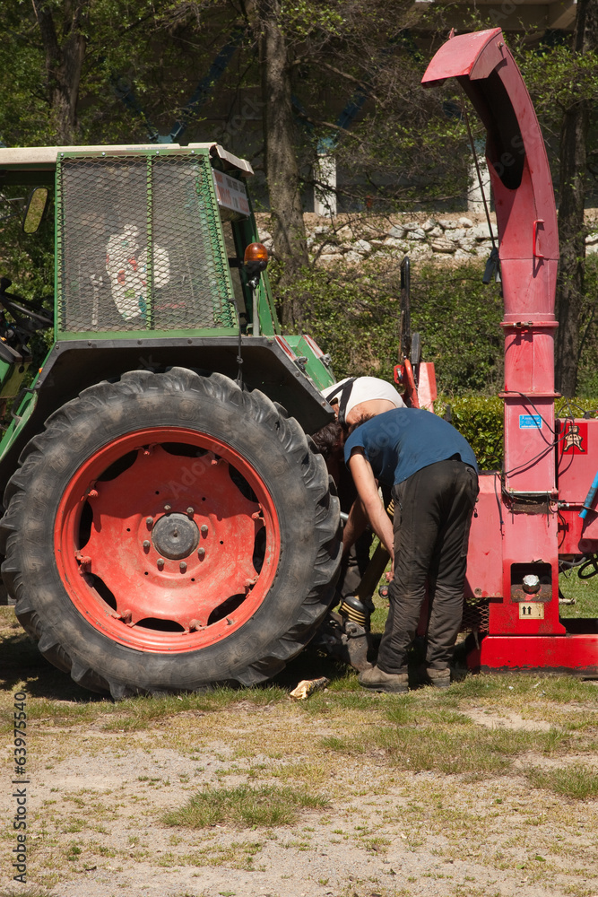Obraz premium En panne ? Un agriculteur examine son tracteur