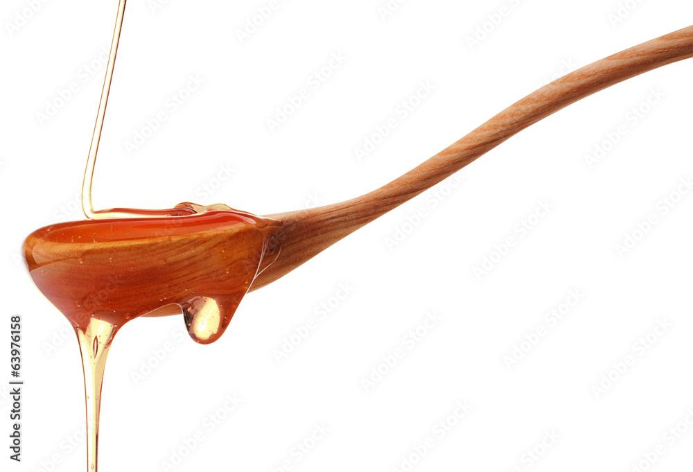 Honey dripping from a wooden honey dipper isolated on white back