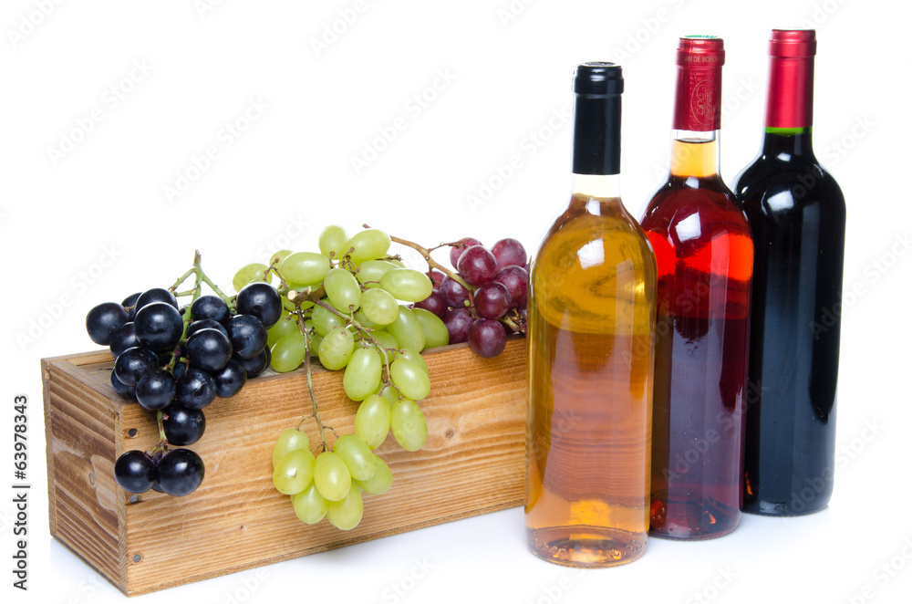 Obraz premium Bottles of wine in front of a wooden box with grapes
