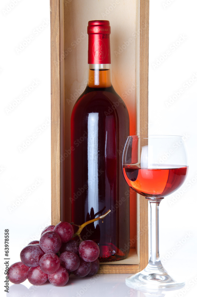 Bottles of wine in a wooden box with a glass of wine and red gra