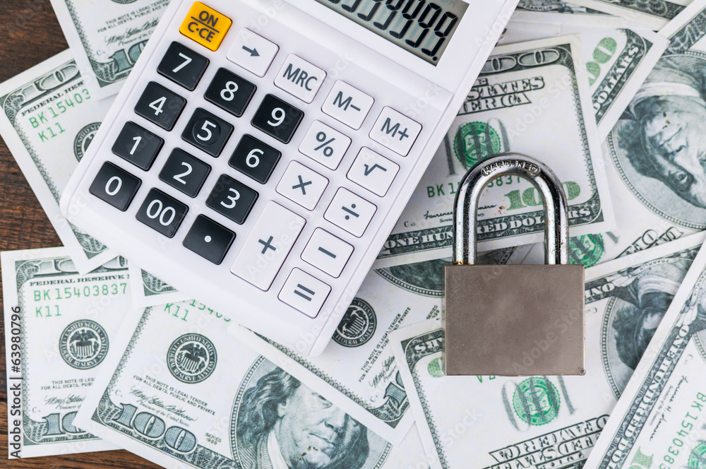 lock and calculator on dollar bill background. lock and calculator on dollar bill background.