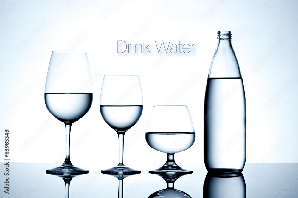 Glassware and bottle filled with water on white background Glassware and bottle filled with water on white background