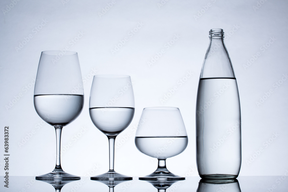 Glassware and bottle filled with water on white background Glassware and bottle filled with water on white background