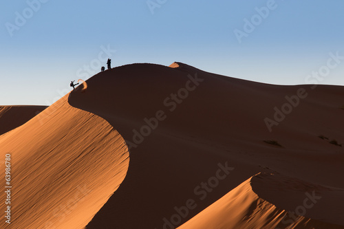 Photographers playing on dunes of desert Sahara, Morocco