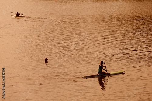 Silhouette of woman paddleboarding at sunset, Florence river, It photo