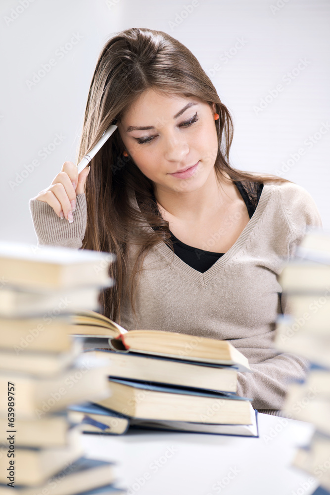 Beautiful girl learning and thinking between many books. Beautiful girl learning and thinking between many books.