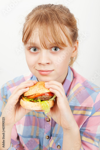 Little blond girl with homemade burger on white background