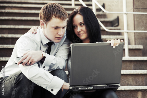 Young business man and woman using laptop outdoor