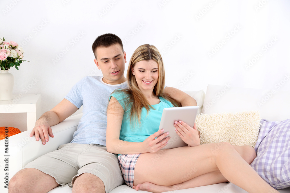 Loving couple relaxing with tablet, on home interior Loving couple relaxing with tablet, on home interior
