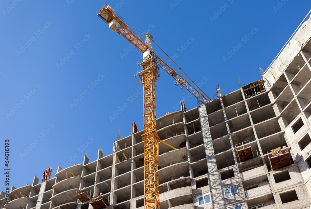 Tall buildings under construction with crane against a blue sky