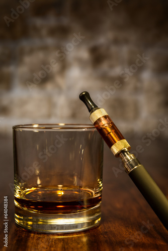 Stillleben mit E-Zigarette und Glas Bourbon