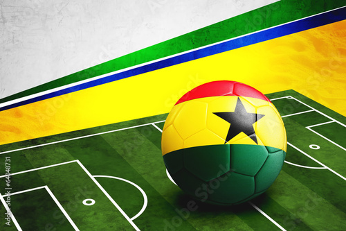 Soccer ball with Ghana flag on pitch