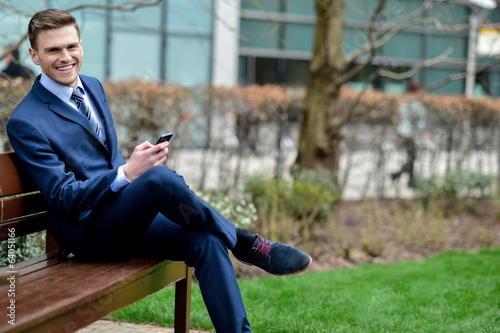 Businessman with his phone on the bench