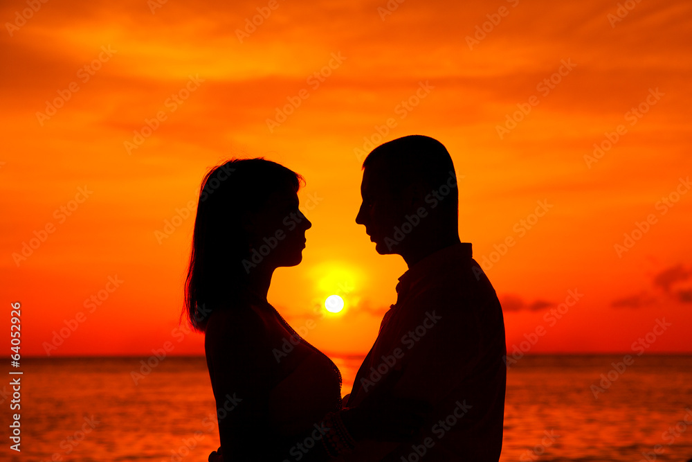 Romantic couple kissing at tropical beach with sunset in the bac