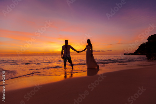 bride and groom on a tropical beach with the sunset in the backg