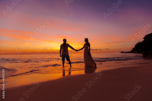 bride and groom on a tropical beach with the sunset in the backg © frolova_elena