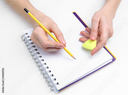 Human hands with pencil and erase rubber and notebook, isolated