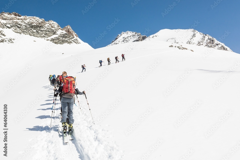 Line of people ascending a mountain on skies