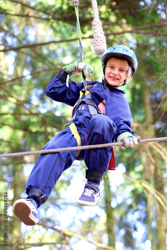 Happy school boy climbing in adventure park