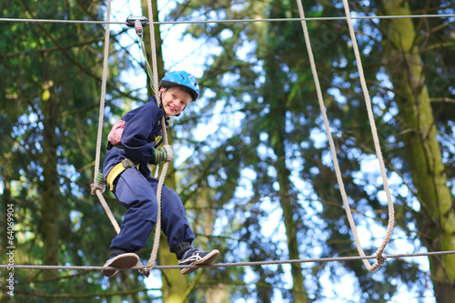 Happy school boy climbing in adventure park