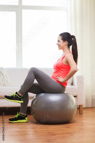 smiling redhead girl exercising with fitness ball