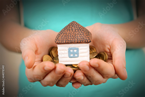 Little house-toy and coins in woman hands close-up photo