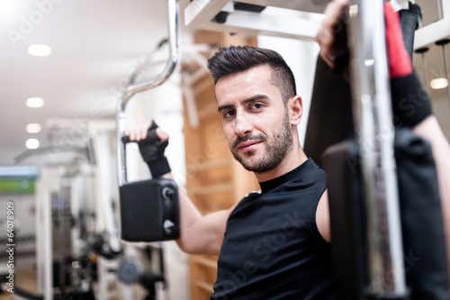 Handsome man working out at gym, daily chest exercise routine