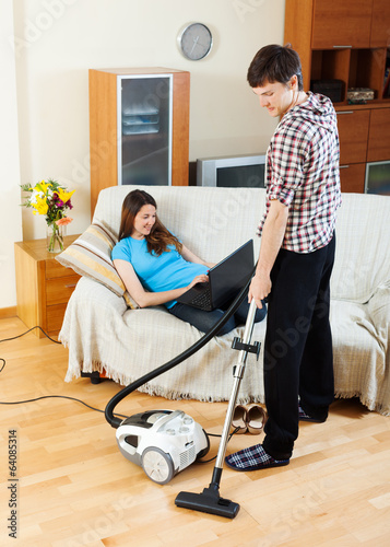  man cleaning  while girl lying with notebook photo