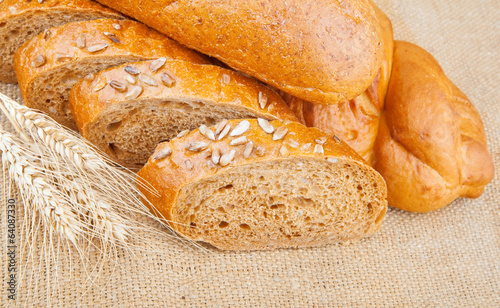 Assortment of baked breads with spikelets of wheat on burlap