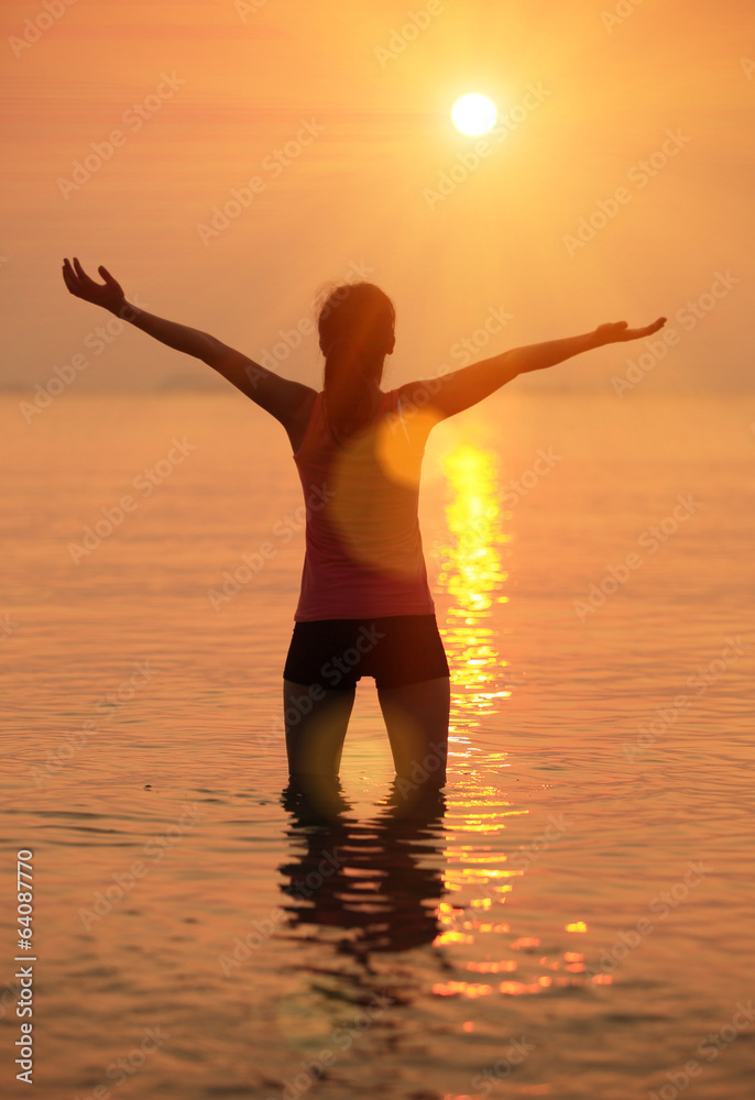 cheering woman open arms under the sunrise at sea 