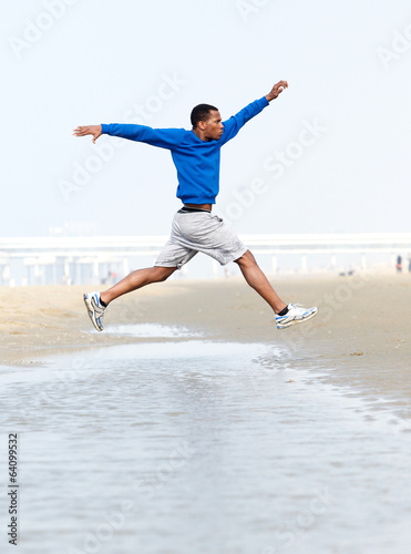Athletic man running and jumping at beach