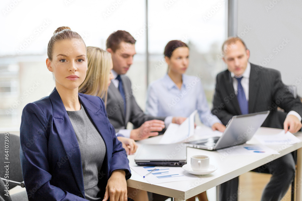businesswoman in office with team on the back businesswoman in office with team on the back
