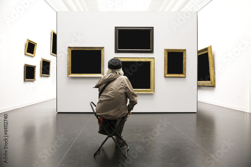 Old lady sitting in art gallery viewing painting