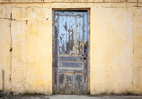 Old wooden door in yellow wall. Background photo texture © evannovostro