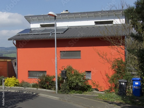 Modernes Passivhaus mit Fassade in blassem Rot bei Sonnenschein im Dorf Vetzberg bei Rodheim-Bieber in der Gemeinde Biebertal bei Gießen an der Lahn in Hessen photo