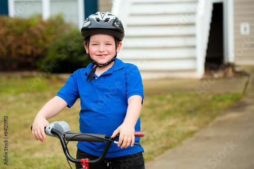 Happy child riding his bike outside his home